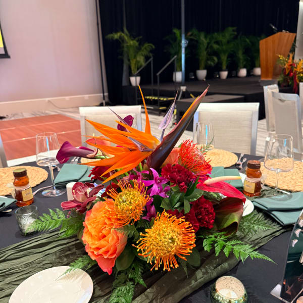 Tropical floral centerpiece with orange and purple blooms on a banquet table