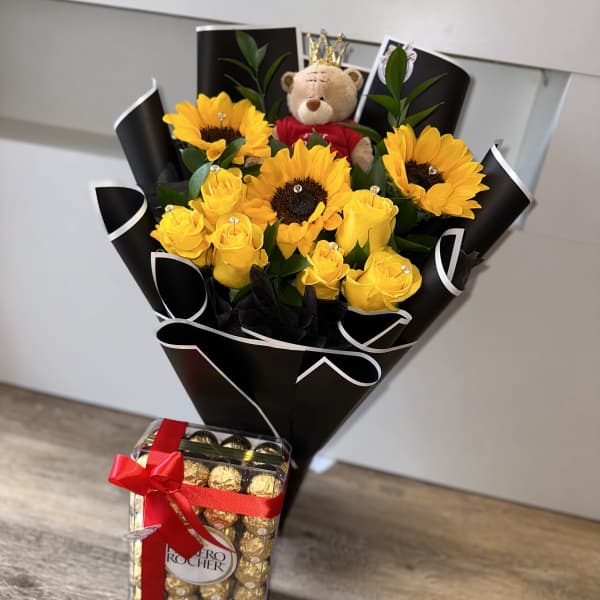 Bouquet of yellow roses and sunflowers with a teddy bear and chocolates
