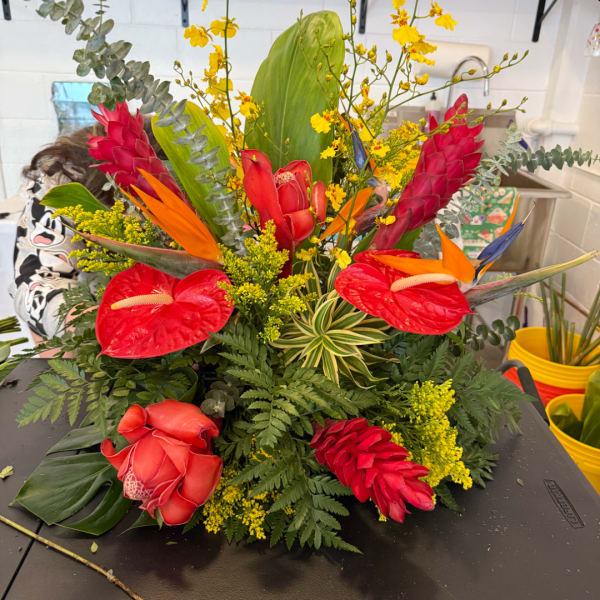 Tropical arrangement with red anthuriums, ginger, and yellow orchids
