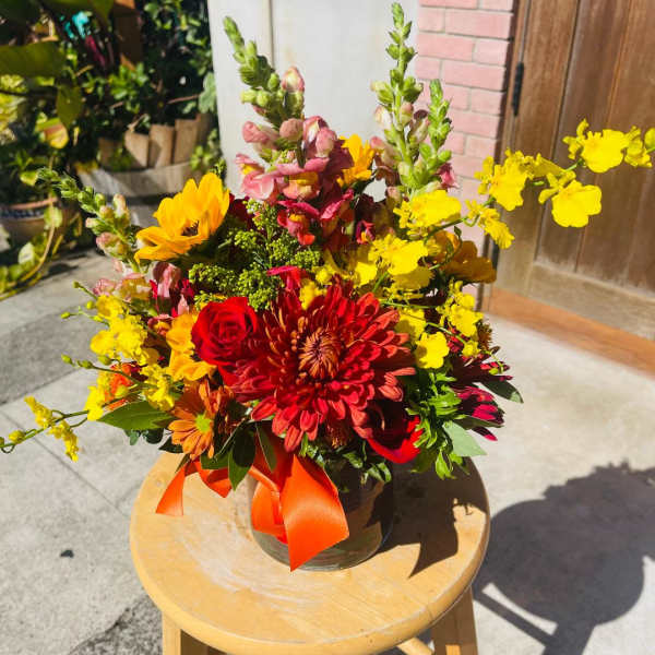 Bright mixed bouquet in a glass vase with red, yellow, and orange flowers