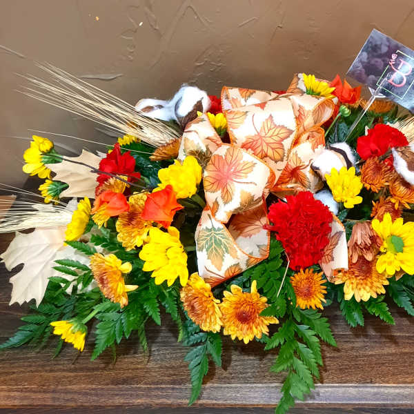 Autumn floral arrangement with yellow and red flowers and a leaf-patterned bow