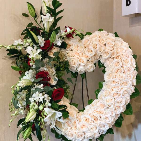 Heart-shaped floral wreath of cream roses with red and white lilies