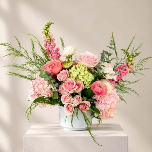 Pink and white floral arrangement in a pale blue vase