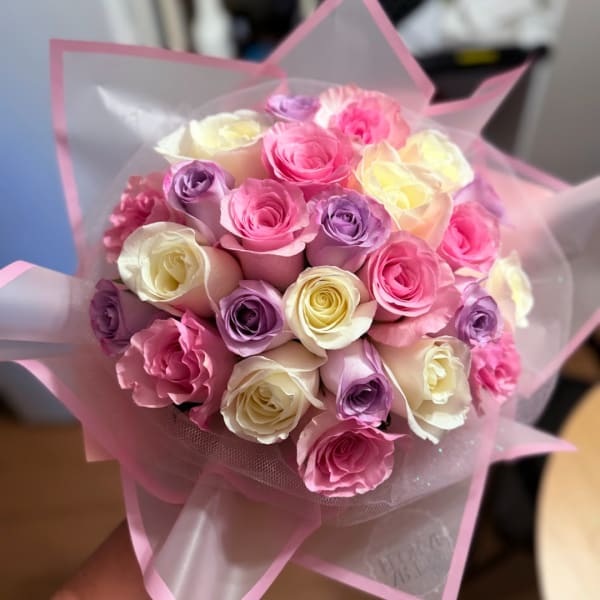 Bouquet of pink, lavender, and cream roses wrapped in pink paper