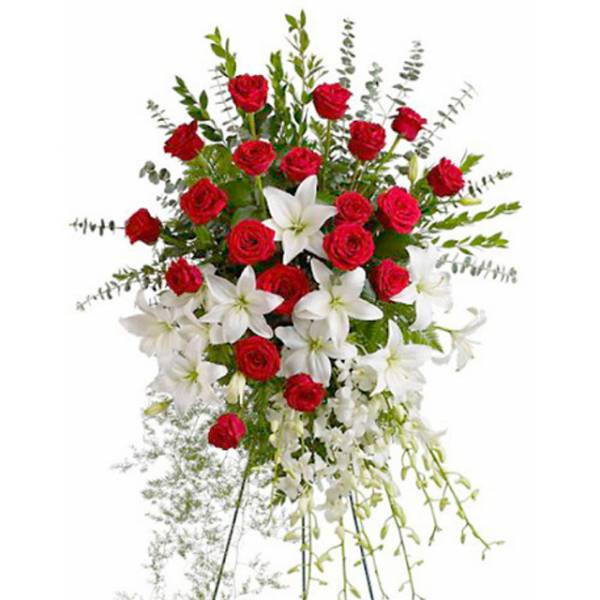 Standing spray of red roses and white lilies with cascading white blooms on a metal easel.