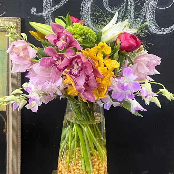 Mixed bouquet of orchids and lilies in a clear glass vase