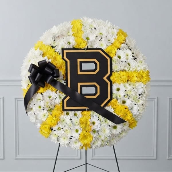 Round floral wreath of white and yellow daisies with a black letter B and ribbon