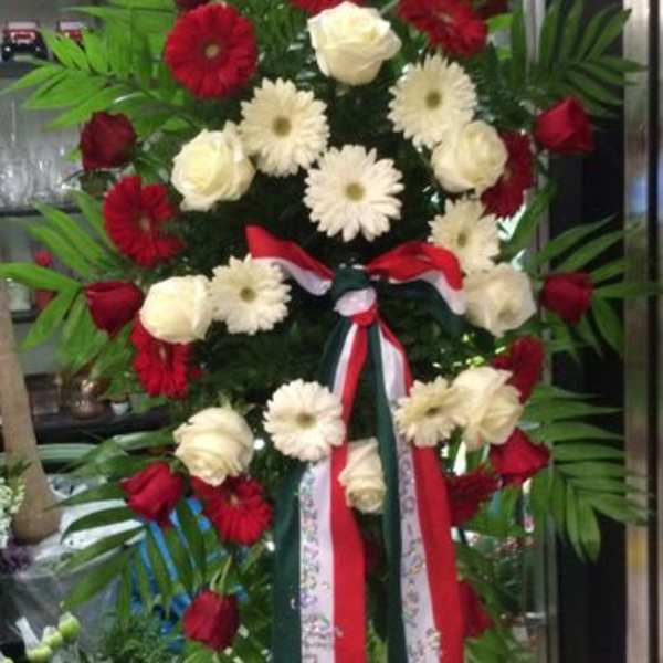 Tall standing floral spray with red and white flowers and ribbon streamers