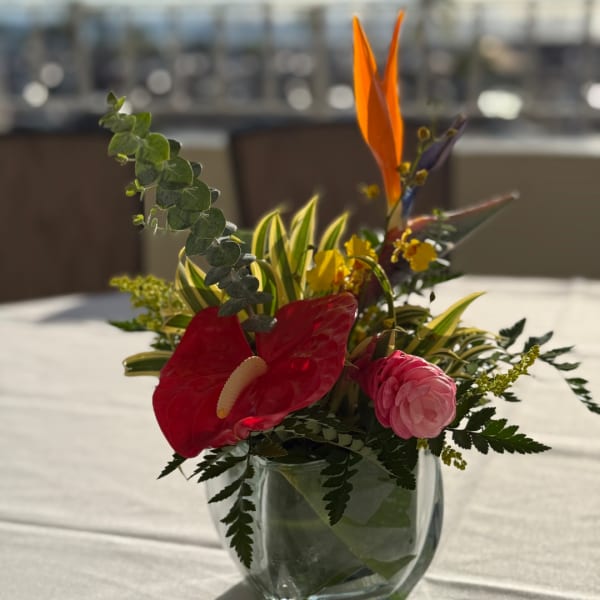 Tropical flower arrangement in a clear glass vase with red and pink blooms
