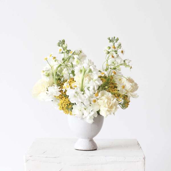White and pale yellow flowers arranged in a gray vase