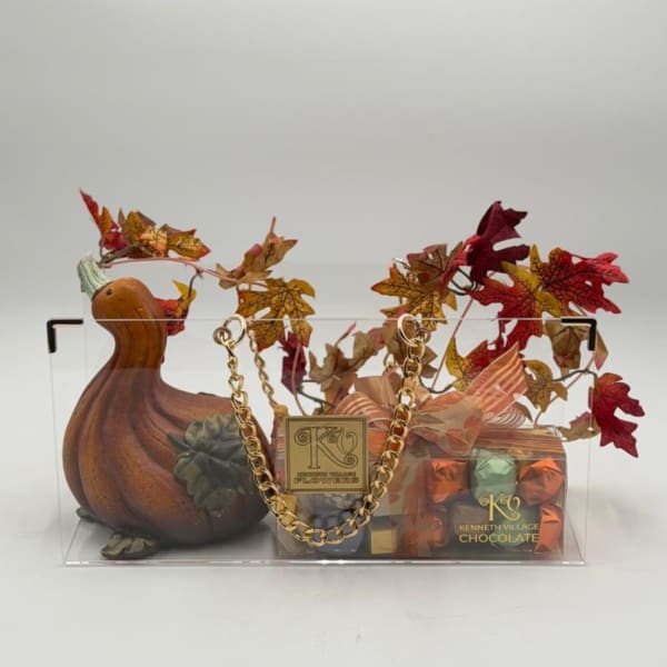 Pumpkin-shaped gift basket with autumn leaves and chocolates