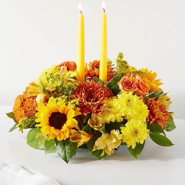 Yellow and orange floral centerpiece with two tall candles