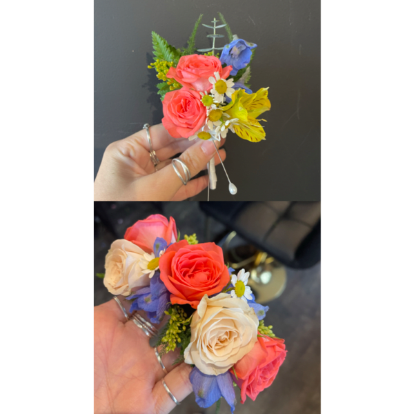 Small hand-held corsage with coral, cream, and blue flowers
