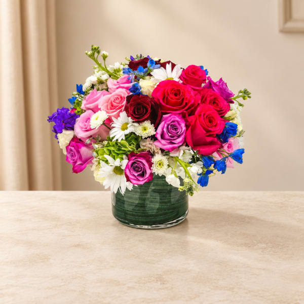 Mixed bouquet of roses and daisies in a green glass vase