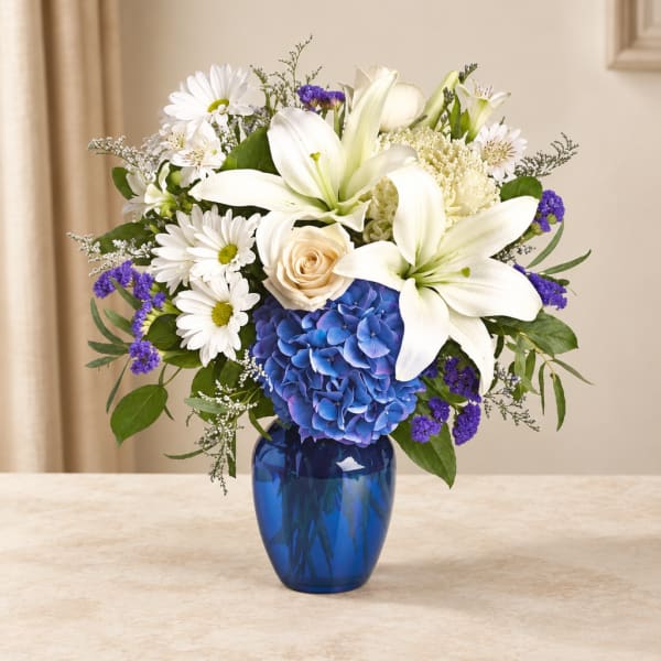 White lilies, daisies, and blue hydrangea in a blue vase