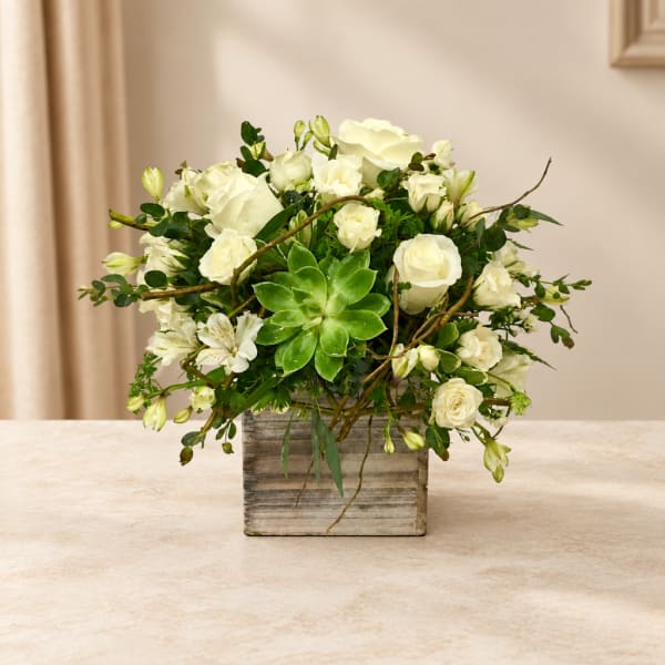 White roses and alstroemeria in a square wooden vase with a green succulent center