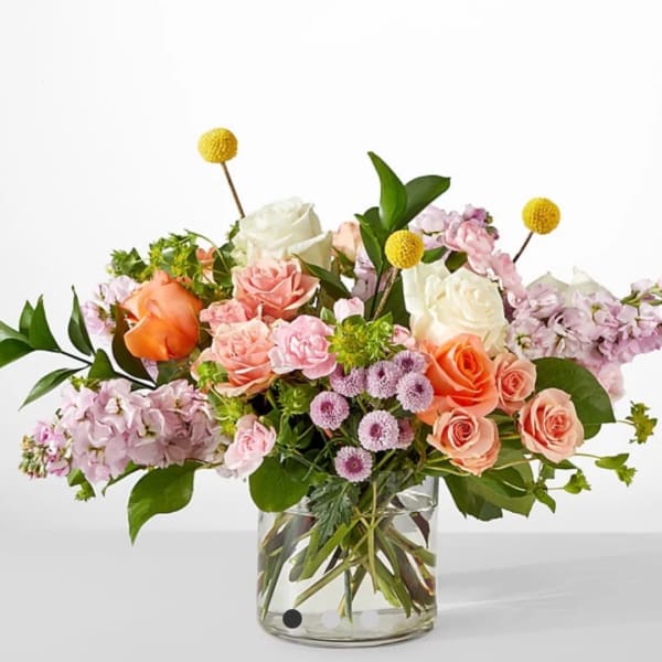 Mixed bouquet of roses and pastel flowers in a clear glass vase