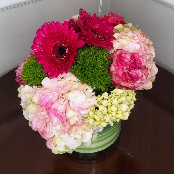 Pink and cream floral arrangement in a striped vase with bright green accents