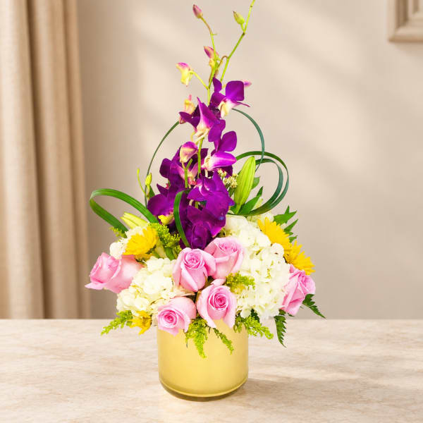 Pink roses and white hydrangeas in a yellow vase with purple orchids