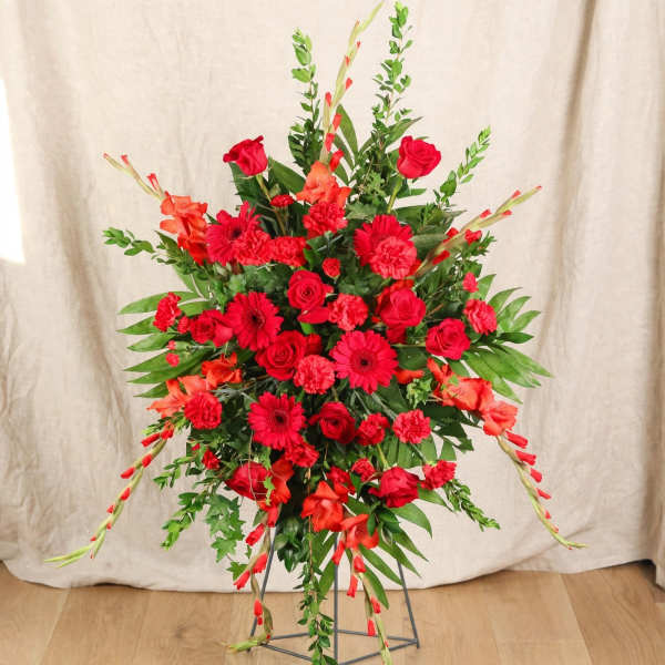 Large red floral standing arrangement with roses, gerberas, and gladiolus