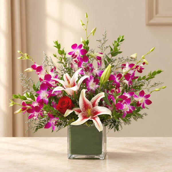Bouquet of pink orchids, white lilies, and a red rose in a glass vase