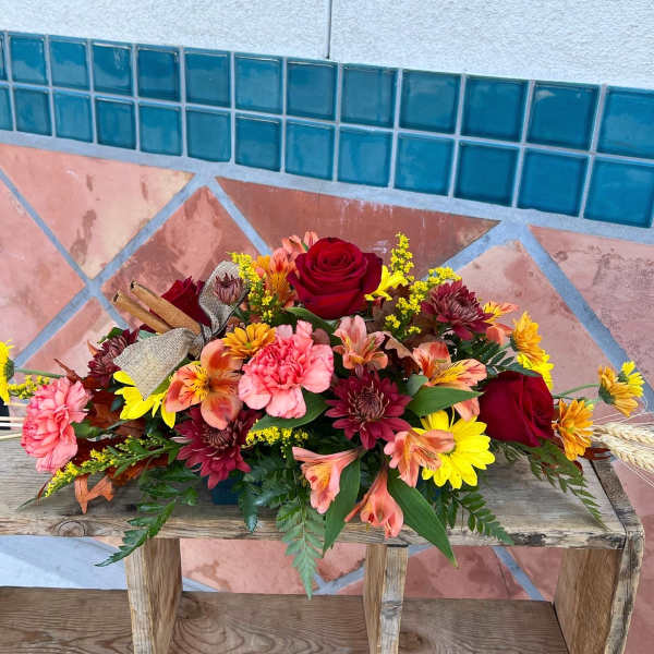 Mixed bouquet of roses, carnations, and daisies on a wooden bench