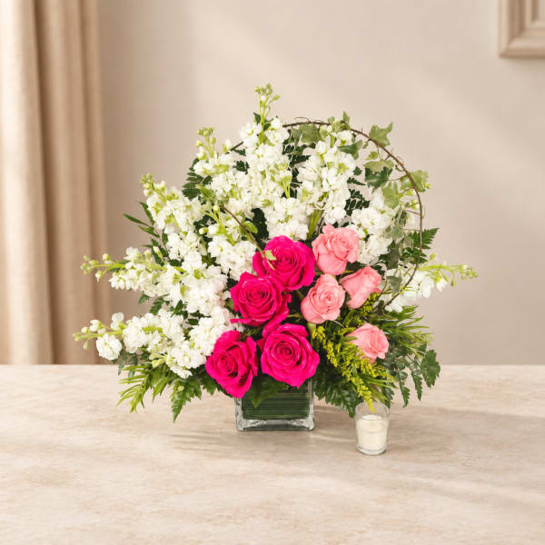 Pink and white rose arrangement in a square glass vase