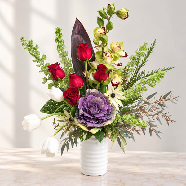 Mixed bouquet in a white vase with red roses, purple cabbage, white tulips, and orchids
