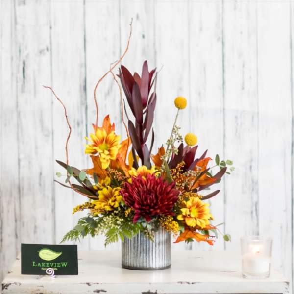Autumn floral arrangement with red and yellow blooms in a ribbed metal vase