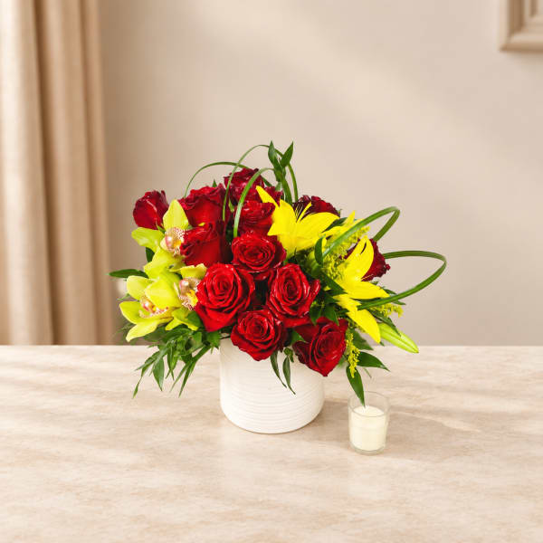 Red roses and yellow lilies arranged in a white vase