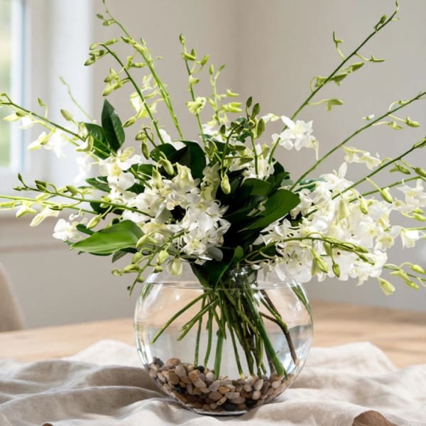 White orchid arrangement in a round glass vase with pebbles