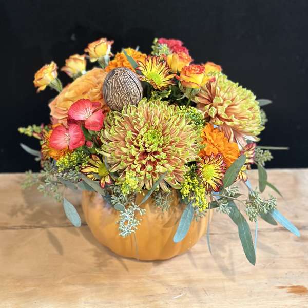 Mixed orange and pink flowers arranged in a pumpkin-shaped container
