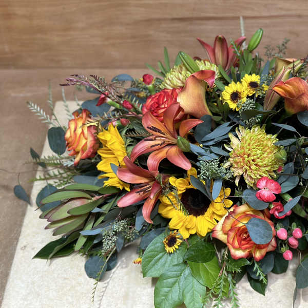 Low floral centerpiece with orange lilies, roses, and yellow sunflowers