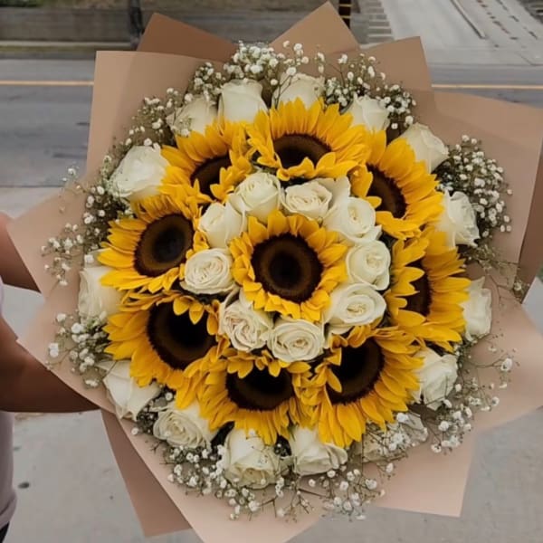 Bouquet of sunflowers and white roses wrapped in tan paper