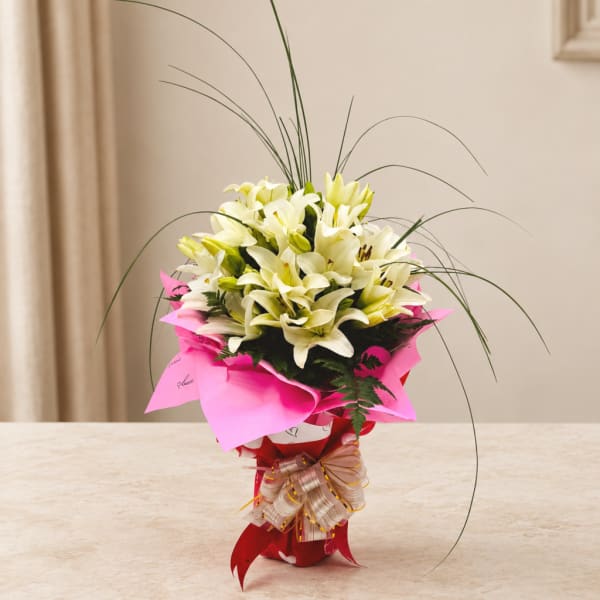 Bouquet of white lilies wrapped in bright pink paper with a ribbon
