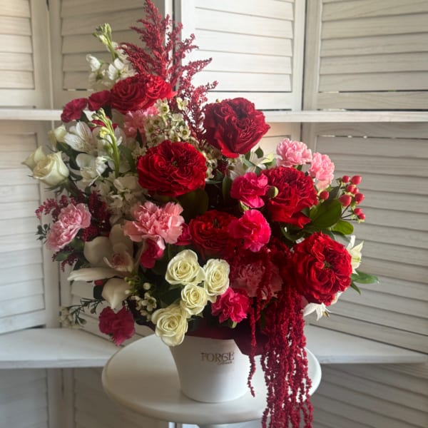 Mixed red, pink, and white floral arrangement in a white vase