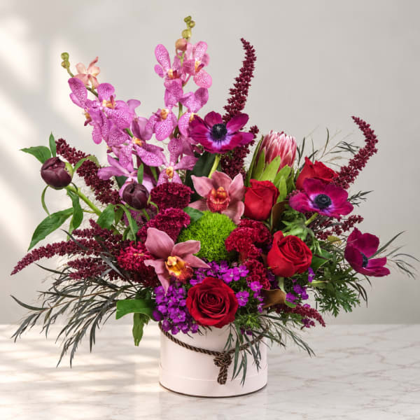 Mixed bouquet in a white round box with pink orchids and red roses