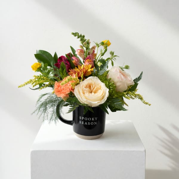Mixed bouquet in a black mug with cream, peach, and yellow flowers