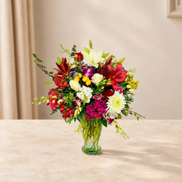 Mixed bouquet of lilies, roses, and orchids in a glass vase