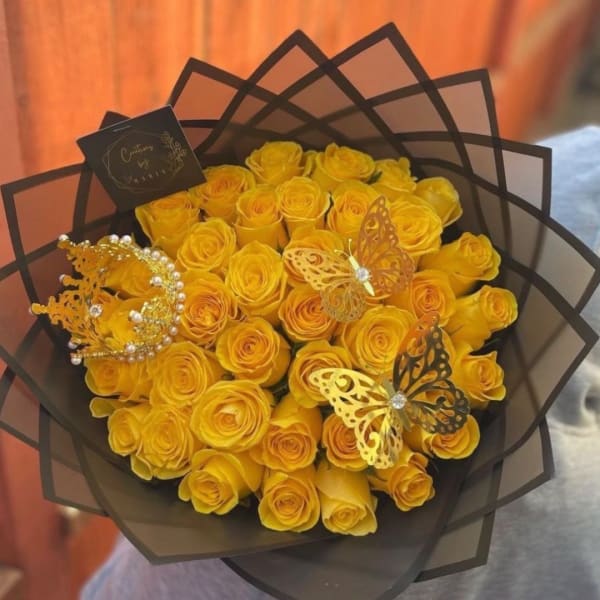 Bouquet of yellow roses wrapped in black paper with butterfly decorations