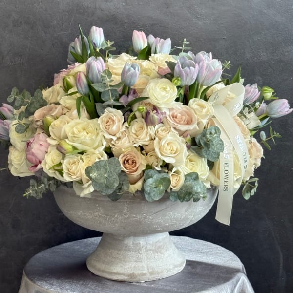 Cream and blush rose bouquet with pastel tulips in a pedestal vase