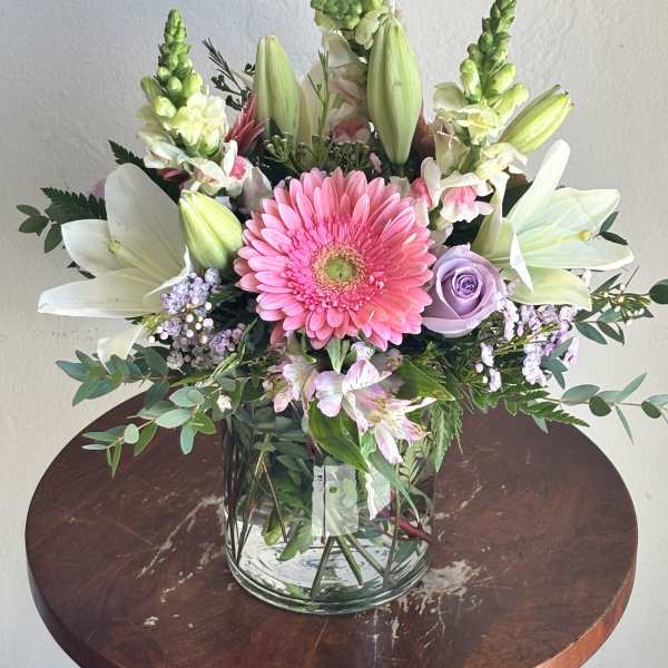Pink gerbera bouquet with white lilies and lavender roses in a glass vase