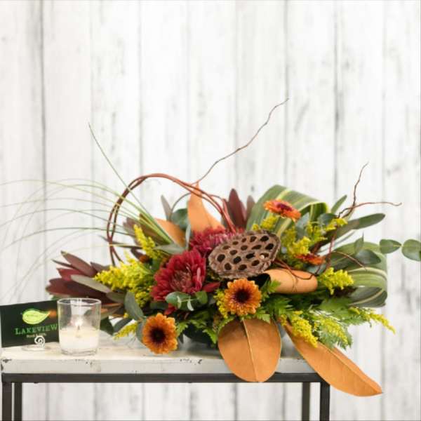 Low floral arrangement with orange and red blooms in a decorative container