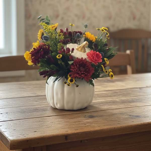Mixed fall flowers arranged in a white pumpkin-shaped vase