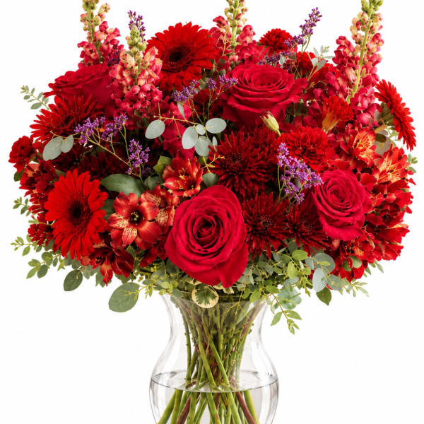 Red roses and mixed red flowers in a clear glass vase
