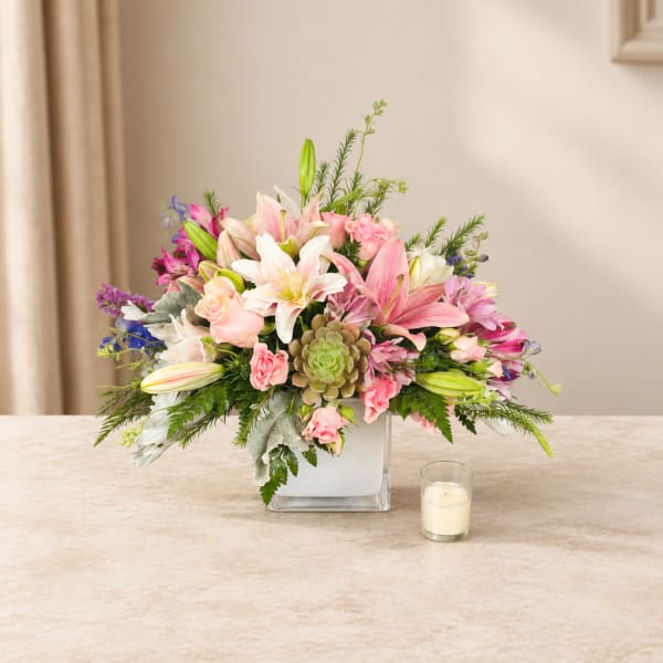 Pink and white floral arrangement in a square glass vase
