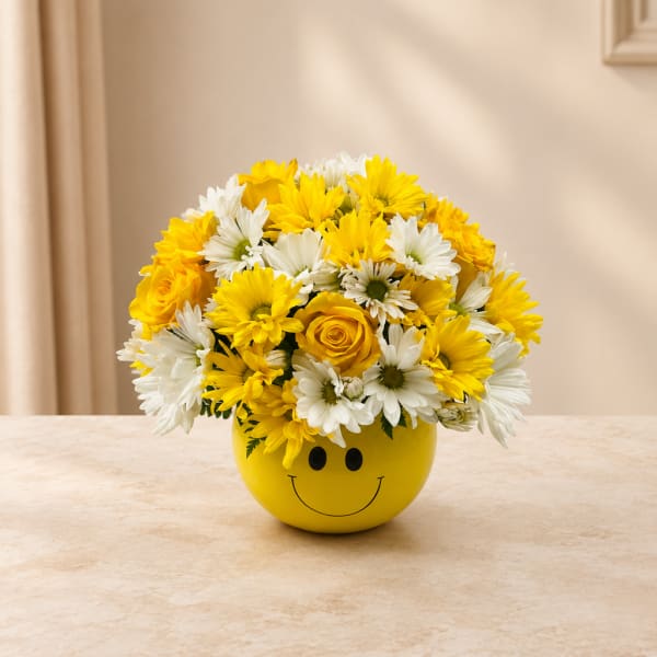 Yellow and white daisy bouquet in a smiley-face pot