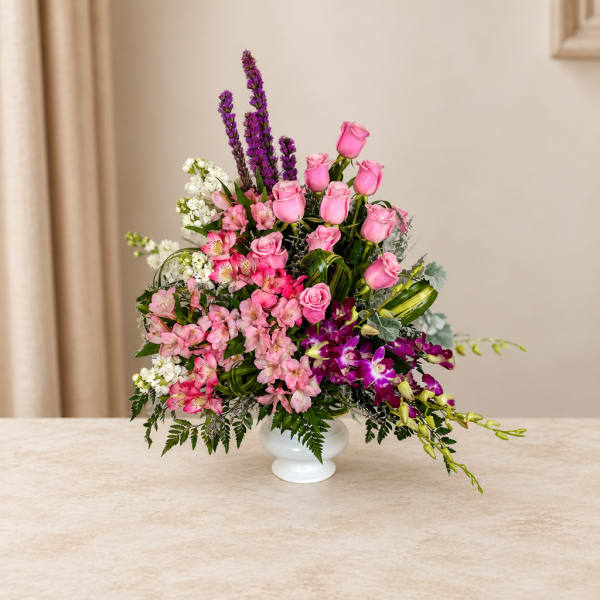 Pink roses and orchids arranged in a white vase