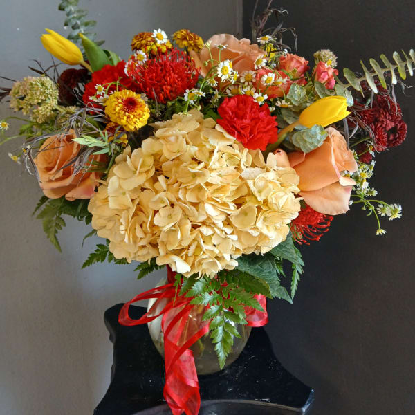 Mixed bouquet in a glass vase with hydrangea, roses, tulips, and daisies