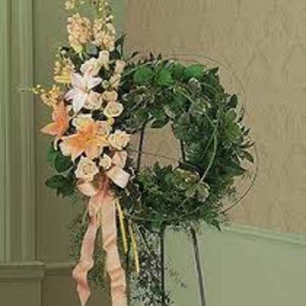 Floral wreath with pale flowers and pink ribbon on a stand